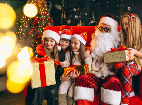 Group of kids sitting with santa and presents on christmas eve